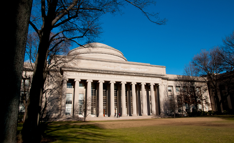 Front budynku Massachusetts Institute of Technology z widocznymi kolumnami i kopułą na tle błękitnego nieba