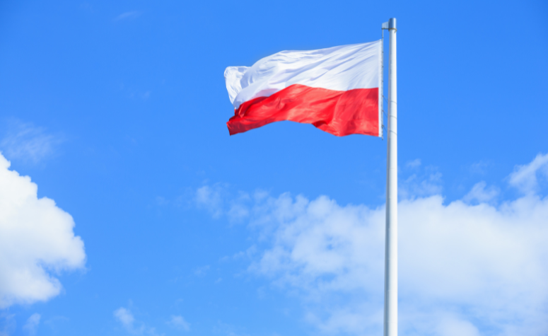 Flaga polska na maszcie powiewająca na tle błękitnego nieba